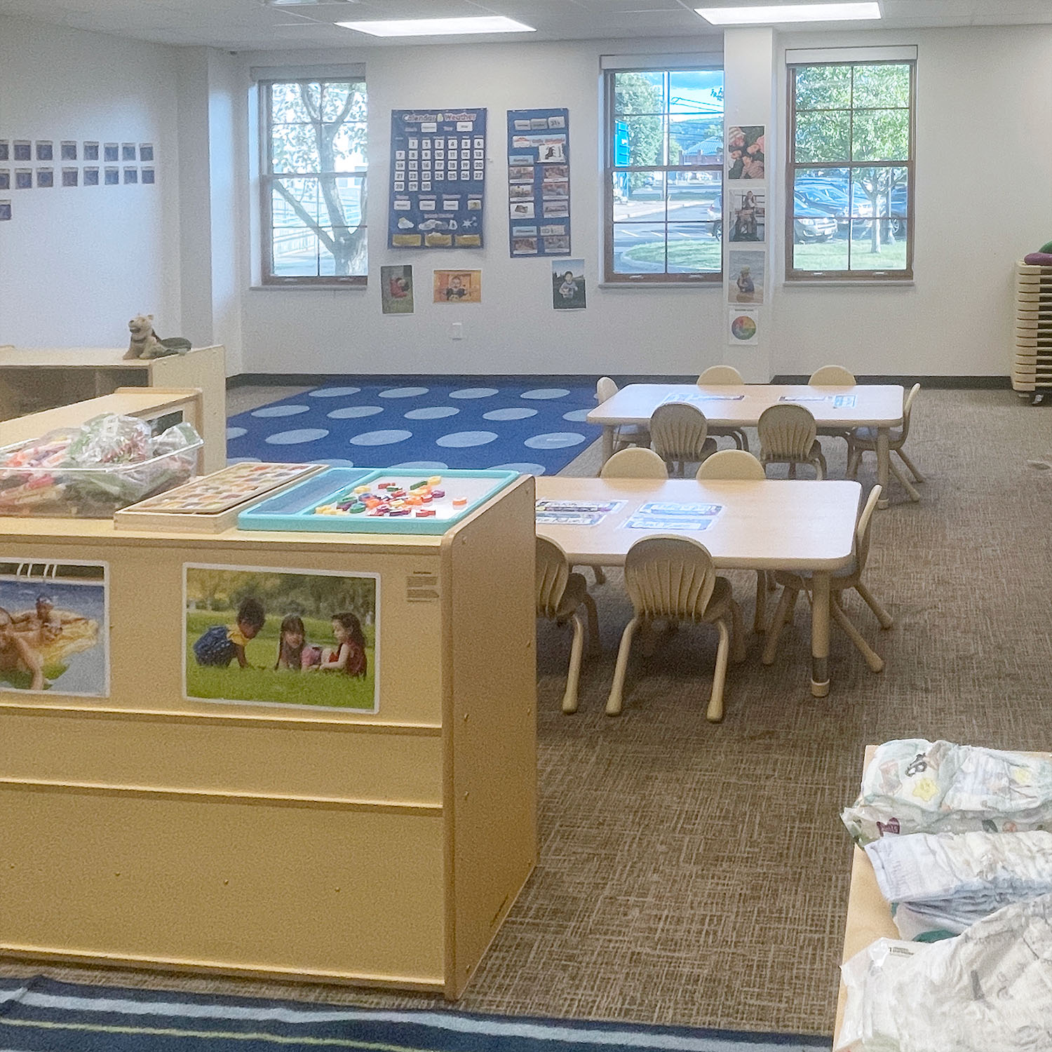 Room in bc体育足球's Early Learning Center, featuring tables, shelves, and playmats for children, with posters on the wall